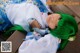 A woman with green hair laying on a wooden bench.