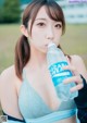 A woman in a sports bra drinking water from a bottle.