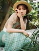 A woman in a straw hat sitting in the grass.