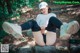 A woman sitting on a rock in the woods.