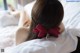 A woman laying on a bed with a red bow in her hair.