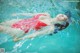 A woman in a red bathing suit floating in a pool.