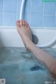 A woman's feet in a bathtub filled with water.