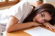 A woman laying on a desk with her head on a piece of paper.