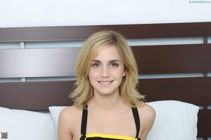 A woman in a yellow and black dress sitting on a bed.